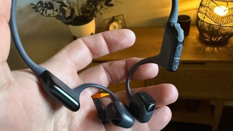 Shokz headphones in hand, showing off buttons and speakers